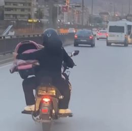 Motosiklet üzerinde bebeği pusetiyle taşıdı